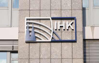 Gebäudefassade, auf der in einem rechteckigen Rahmen das „IHK-Köln“-Logo mit stilisierten Turmspitzen zu sehen ist.