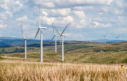 Windräder in einer hügeligen Landschaft.